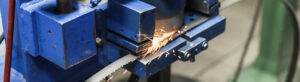 close up image of blue machine cutting a saw blade