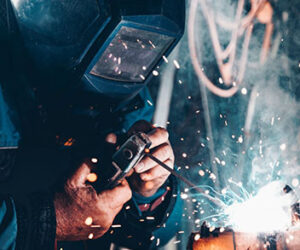 image of man in welding helmet welding, sparks flying
